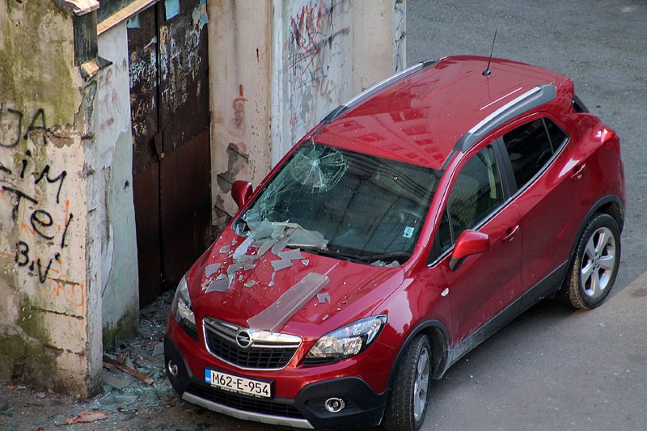 U Tuzli sa zgrade palo armirano staklo i teško oštetilo automobil