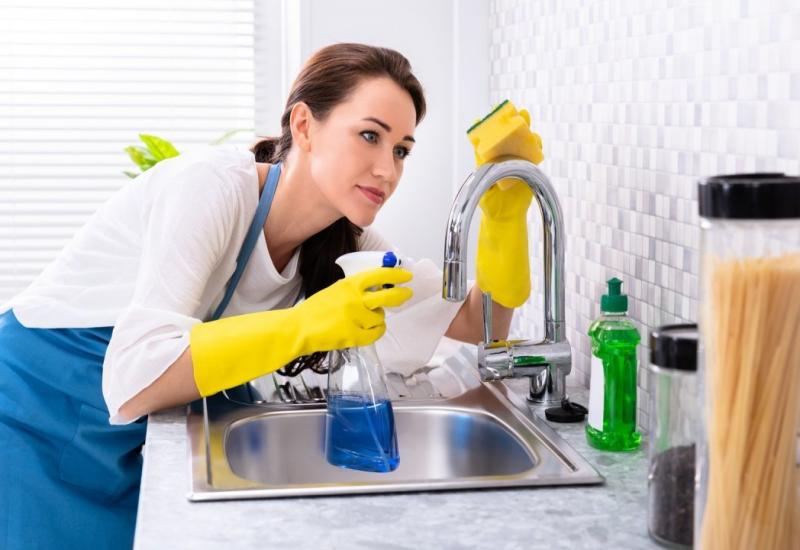 Žena čisti kuhinju - Dobri, stari način za čišćenje kuhinjskog sudopera                 