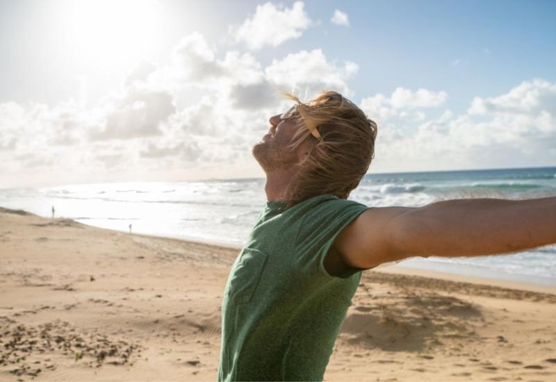 Muškarac s raširenim rukama na plaži - Otkrivamo 10 dobrobiti koje tišina ima na naše zdravlje