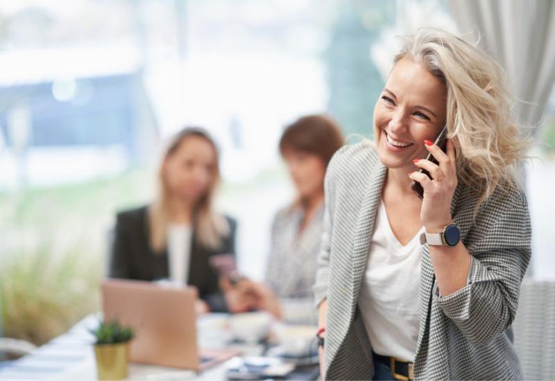 Poslovna žena s mobitelom na sastanku - 10 loših navika zbog kojih ostavljate neprofesionalan dojam